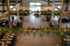 view of event barn from loft area featuring greenery and lighting.