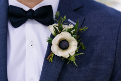 close up of boutonierre on groomsmen in blue tuxedo and bowtie.