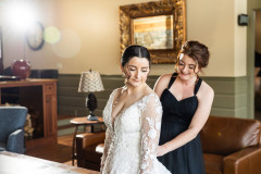 bride with bridesmaids behind her helping put dress on.