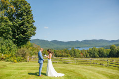 bride and groom exchanging vows with view of lake in background.