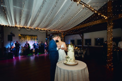 bride and groom kissing under drapery in event barn.