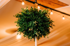 a  kissing ball made of greenery hanging from a celing.
