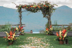 Floral archway with yellow and red flowers and flower petals in pathway toward arch near wooden benches at Mountain Top Inn & Resort in Chittenden, VT