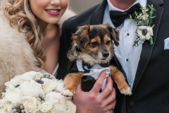 Man and woman in wedding attire holding dog and wedding bouquet at Mountain Top Inn & Resort in Chittenden, VT