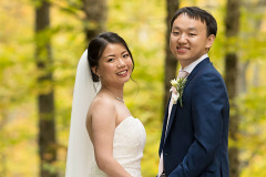Bride and groom standing in front of  yellow foliage leaved trees.