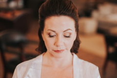 brunette looking down with hair pulled back and wearing a white robe.