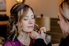 bride with eyes closed while hair for wedding is done and makeup is being done by an artist.