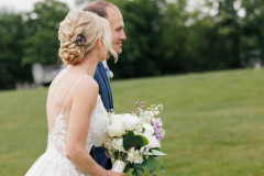 bride in white gown walking with groom holding flowers.