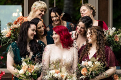 bride and bridesmaids standing together holding bouquets and laughing