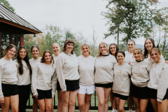 bride with bridesmaids standing in front of camera with tan sweatshirts on.