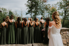 bride standing with bridesmaids in front facing away for a first look