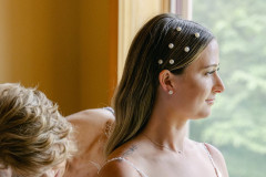 close up of hair design on bride while mother of bride helps with dress.