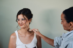 bride with hair and makeup done being lightly brushed for final touches.