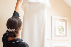 photo of bride with hair in bun holding up wedding dress