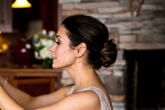 profile of brunette woman with hair in low bun. stone fireplace in background.