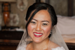 close-up of bride with brown hair, veil and white lacy sleeves on wedding dress.