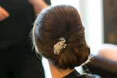 woman with brown hair in bun with flower.