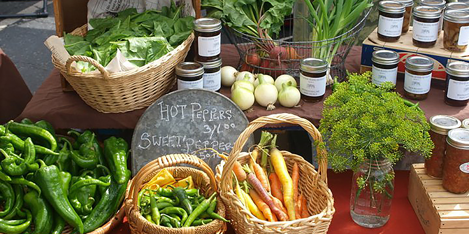 carrots onions peppers beets and jars of food on farmers market table