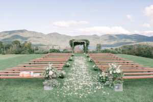 green mountains with wedding knoll and farmhouse benches in front with floral arrangements