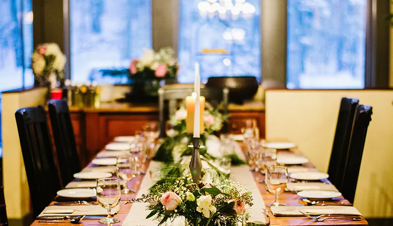 Mountain Top Resort interior of a guest home for a small intimate dinner. Features eight table settings with candles, flowers, and a table runner in the middle of the table and image.